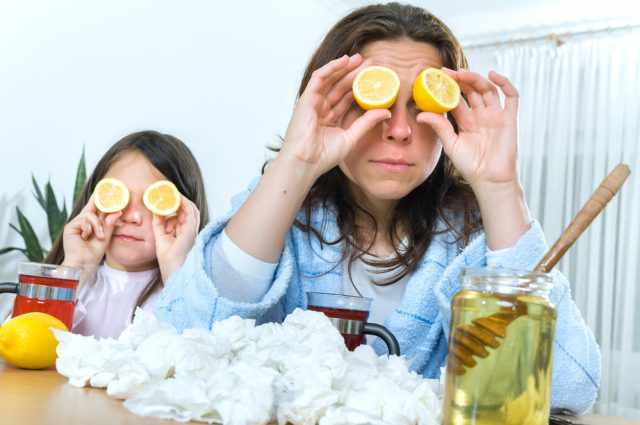 Mother and daughter having tea, eating lemon, honey to heal