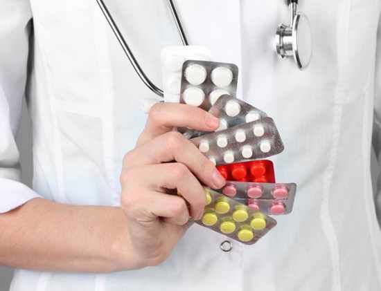 Close-up of female doctor hand holding pills, on color background