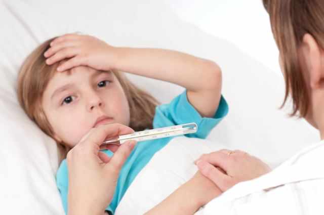 Sick little girl in bed. Mother with thermometer is sitting near the bed. Focus on thermometer.